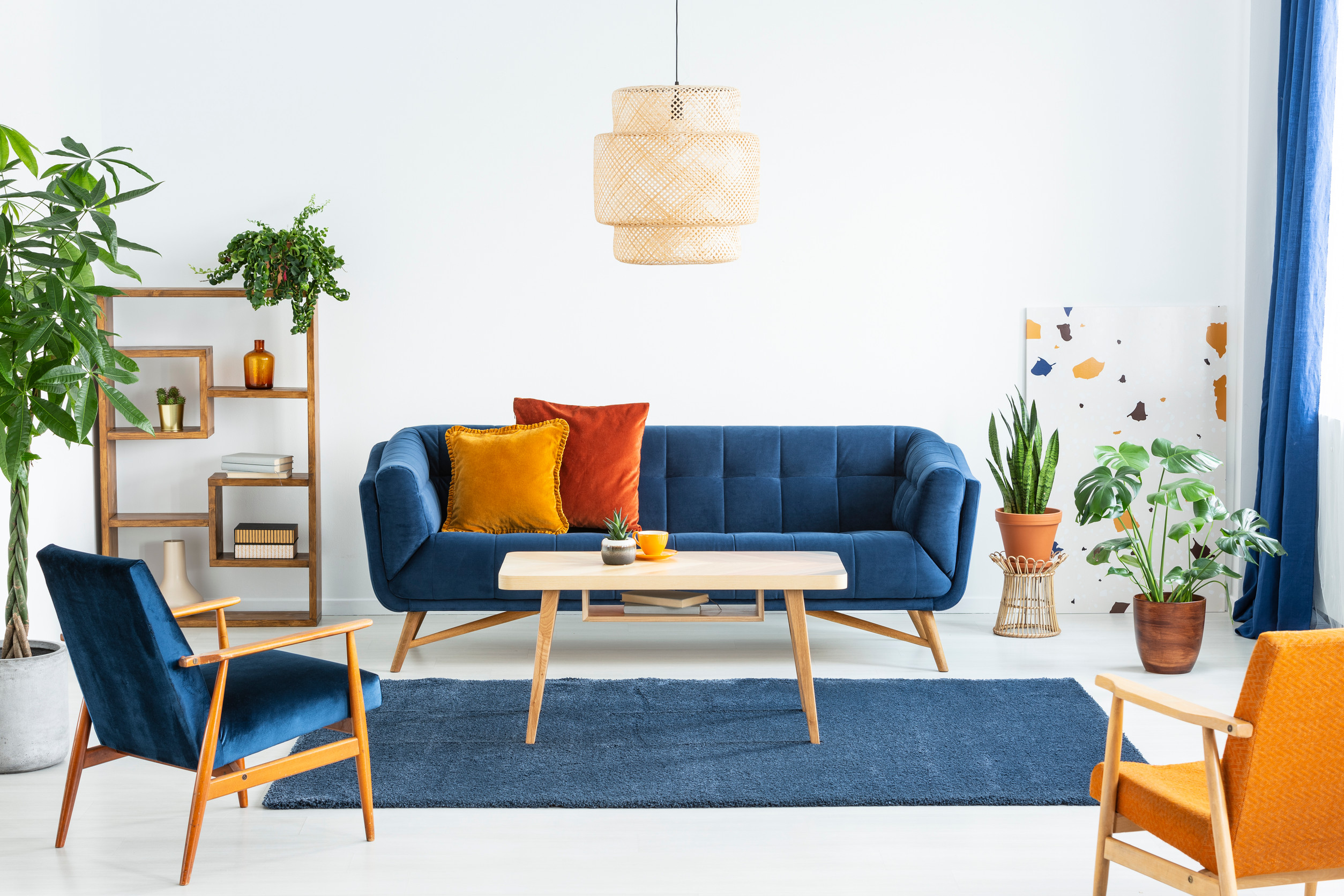 Retro armchairs with wooden frame and colorful pillows on a navy blue sofa in a vibrant living room interior with green plants. Real photo. Retro armchairs with wooden frame and colorful pillows on a navy blue sofa in a vibrant living room interior with green plants. Real photo.