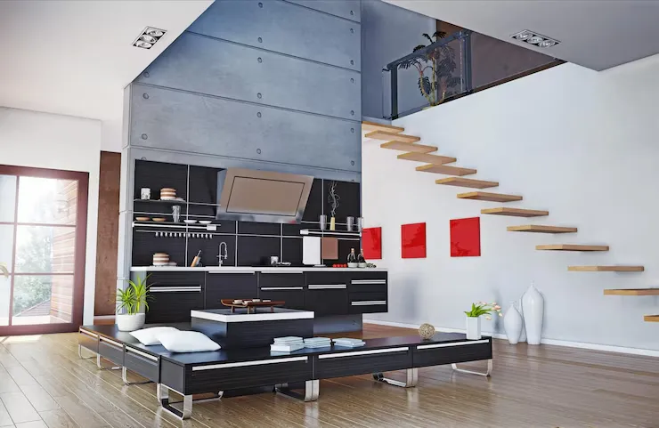Modern open-concept living space featuring a sleek black kitchen, wooden staircase, and minimalist decor with vibrant red accents